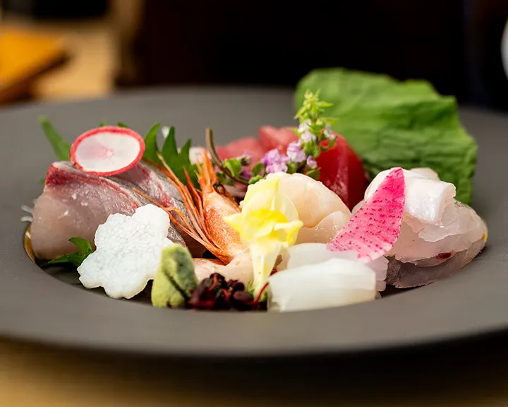魚料理、野菜のトッピングとソースが添えられている