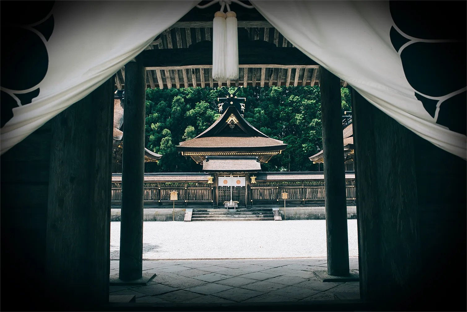 白いのれんがかかった神社の鳥居と、奥に見える社殿。厳かな雰囲気。